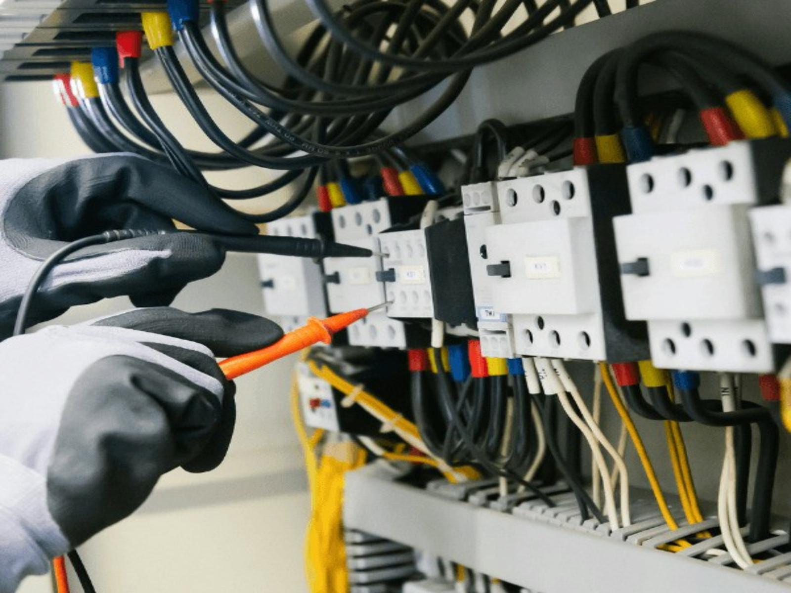 Electrician testing a commercial switchboard with a multimeter